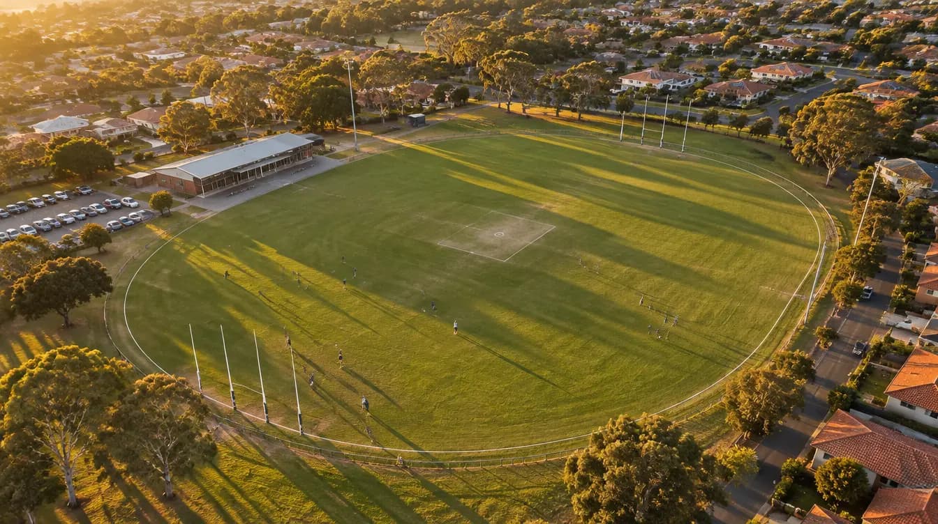 Aerial view of a suburban footy oval with clubrooms at golden hour